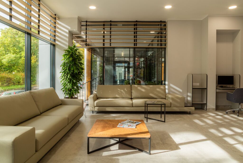 A spacious and modern living room with large windows and natural sunlight illuminating the sleek interior design.