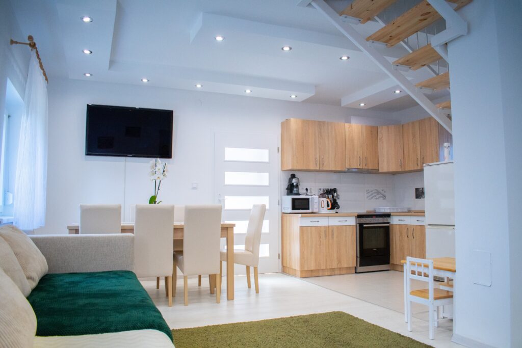 Interior of spacious dining room and kitchen with modern appliances and comfortable chairs and sofa